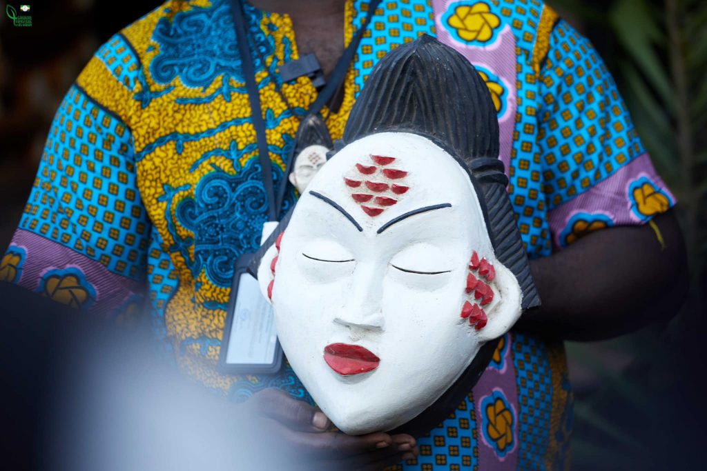 Un artisant tenant dans ses mains un masque Punu